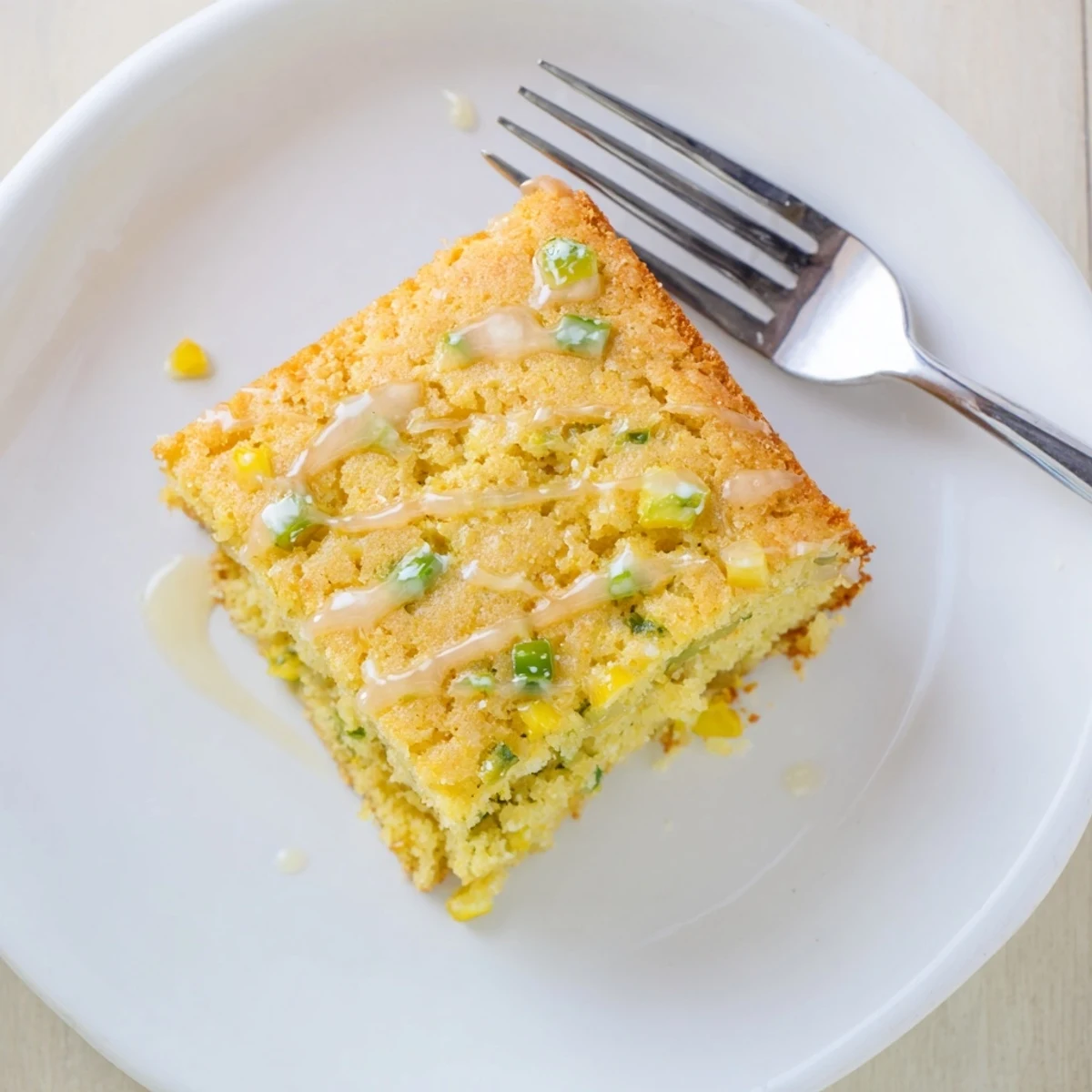 Warm square slices of spicy jalapeño cornbread topped with sweet lime honey glaze and fresh herbs