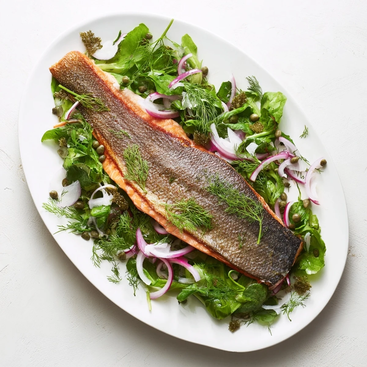 Pan-seared salmon featuring perfectly crisp golden skin atop a zesty herb salad garnish