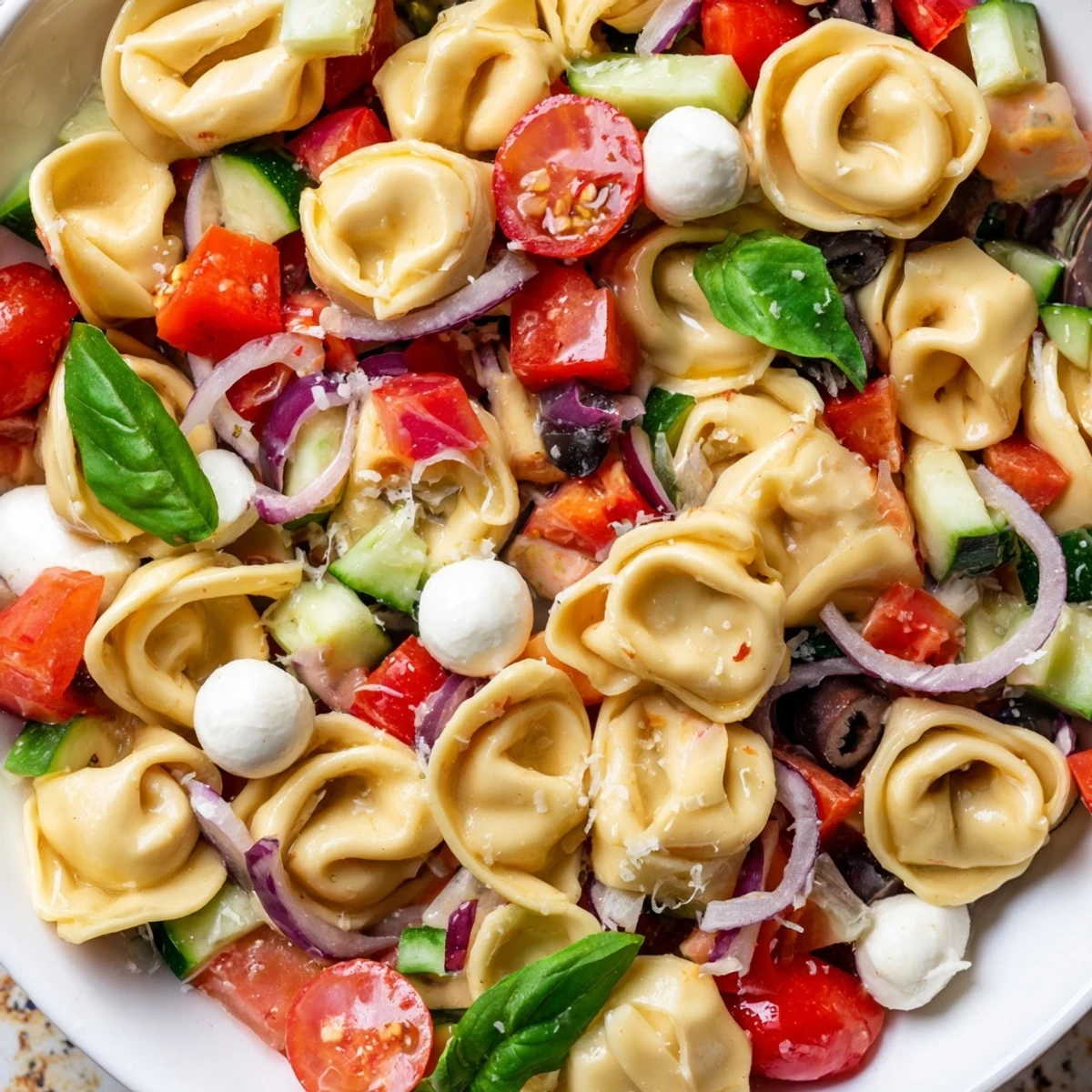 Colorful tortellini salad with cherry tomatoes, cucumber, and mozzarella tossed in Italian dressing