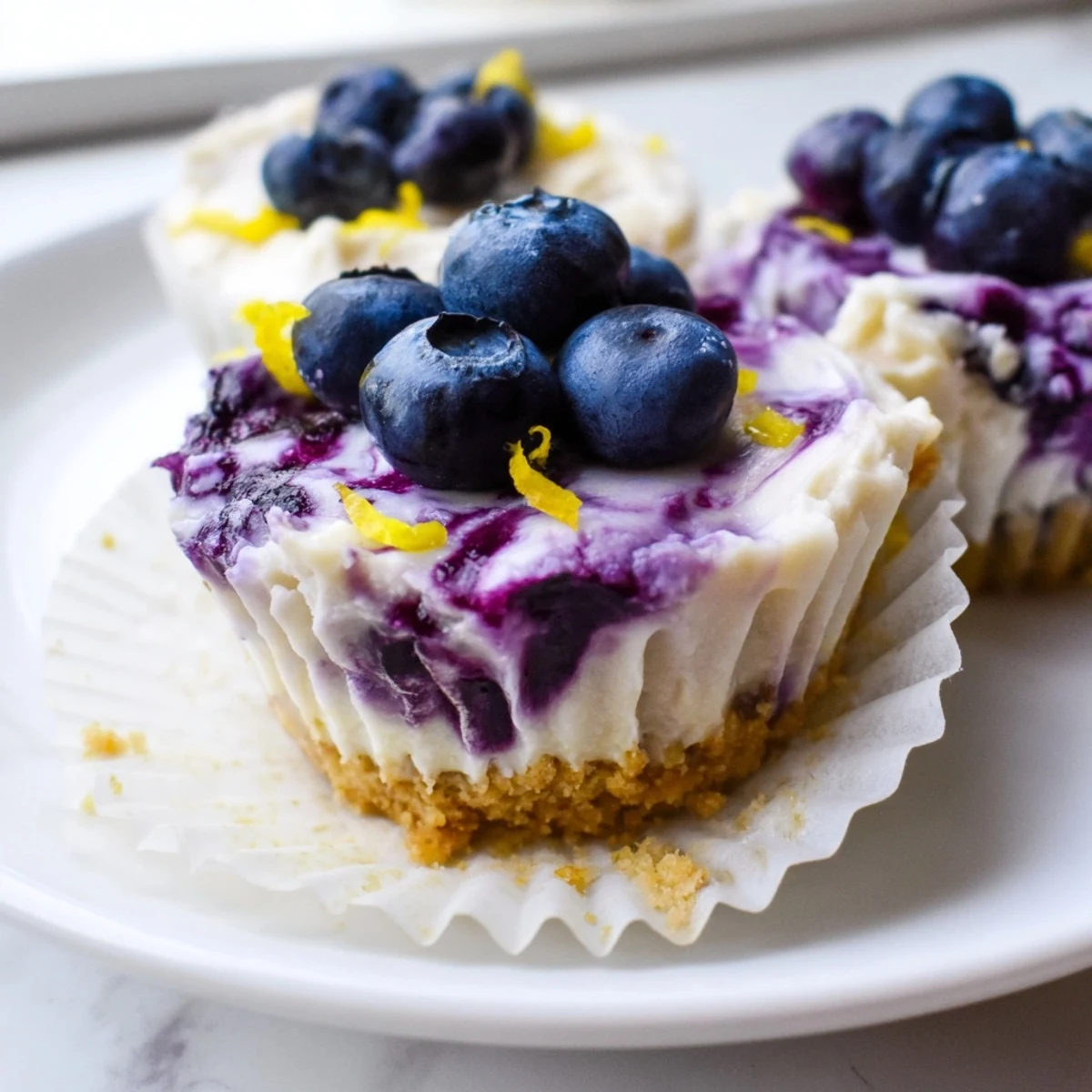 Golden mini lemon blueberry cheesecakes topped with vibrant purple compote in paper liners