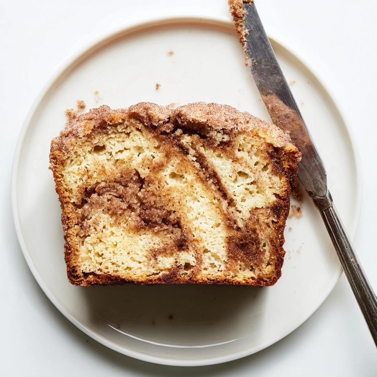 Golden snickerdoodle banana bread sliced on a rustic board with cinnamon-sugar swirl