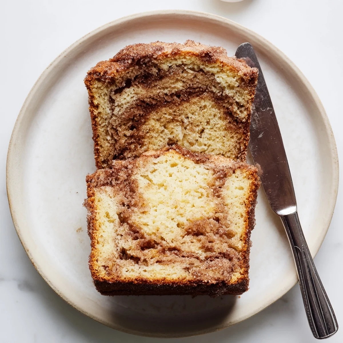 Warm snickerdoodle banana bread loaf topped with crackly cinnamon sugar and butter