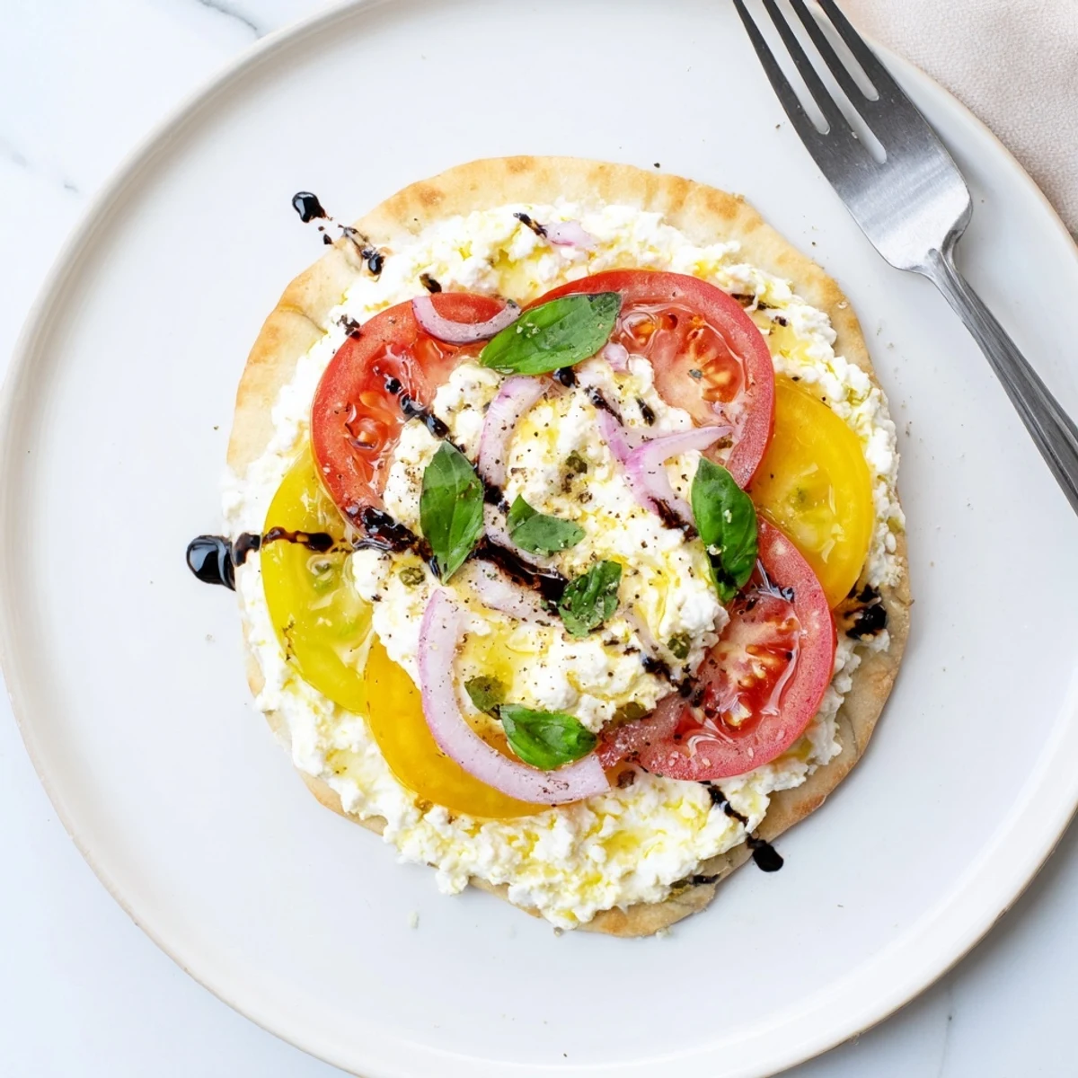 Slices of Caprese Pita Pizza With Whipped Garlic Feta atop parchment, juicy tomatoes