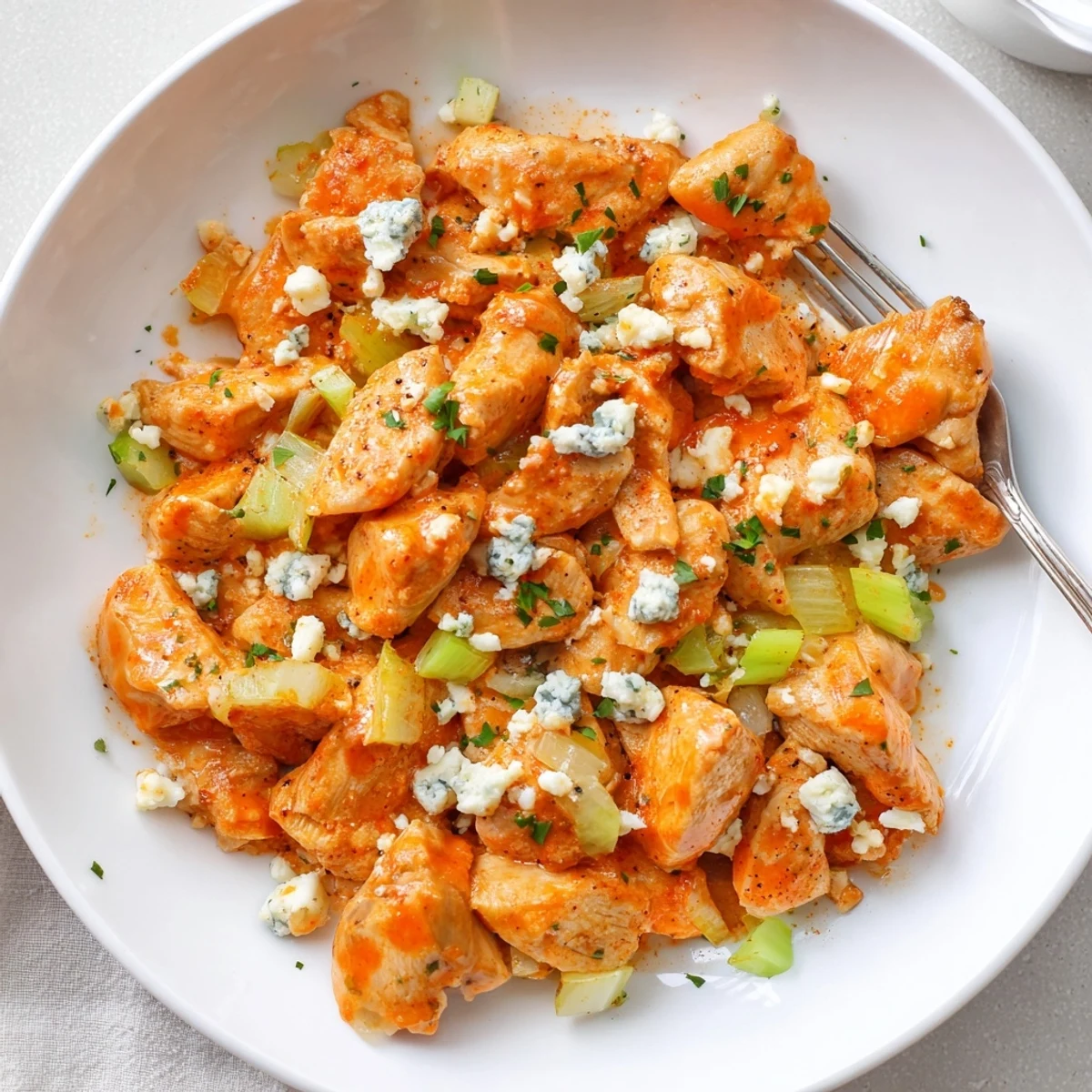 Keto Buffalo Chicken Skillet topped with crumbled blue cheese, served over cauliflower rice