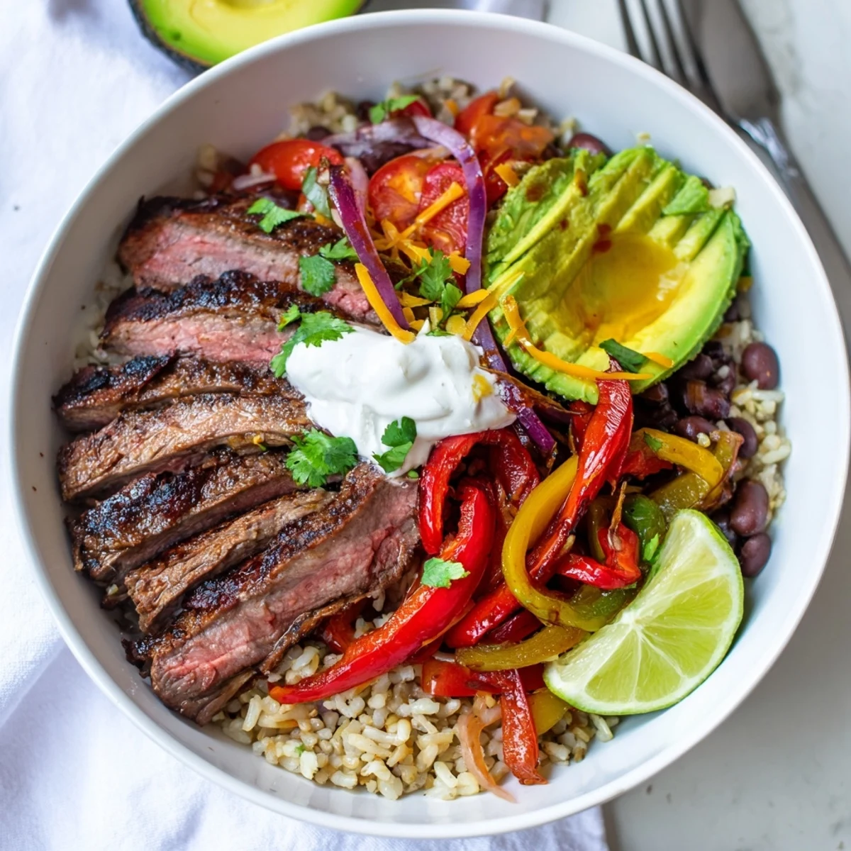 Layered over brown rice, Steak Fajita Power Bowls feature creamy avocado slices.