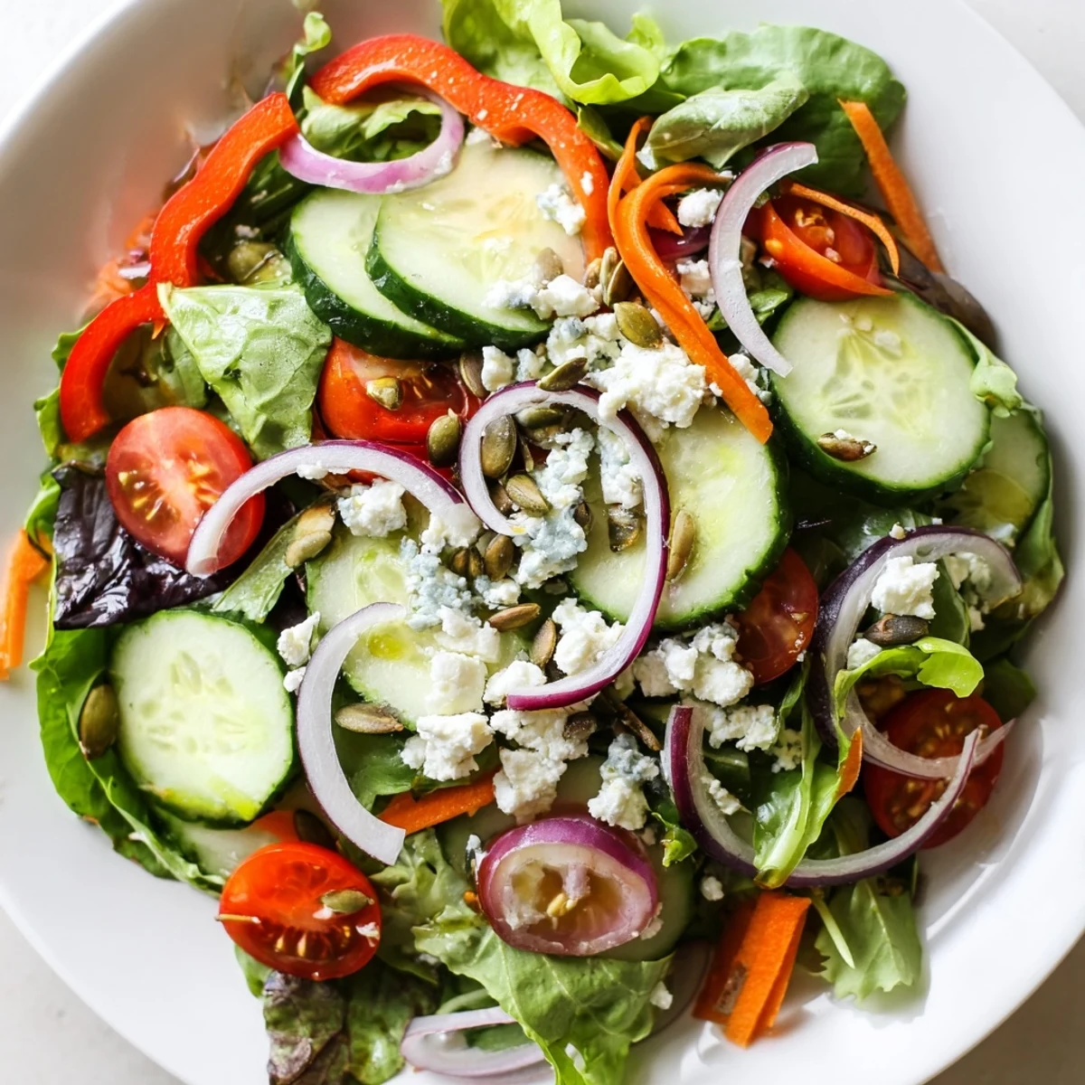 Vibrant medley of mixed greens, sliced cucumber, red bell pepper, and halved cherry tomatoes in garden salad