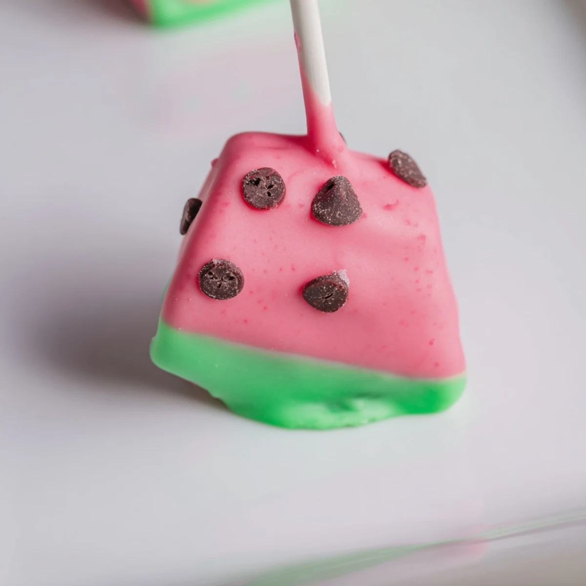 Bite-sized watermelon cake pops with colorful candy coating and lollipop sticks ready for serving