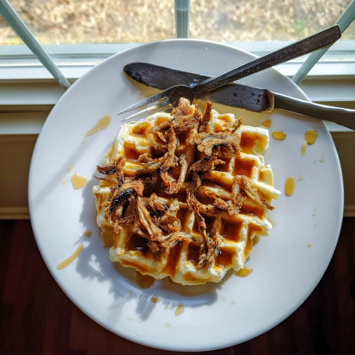 Stack of golden waffles topped with plant-based fried chicken strips and maple hot sauce drizzle