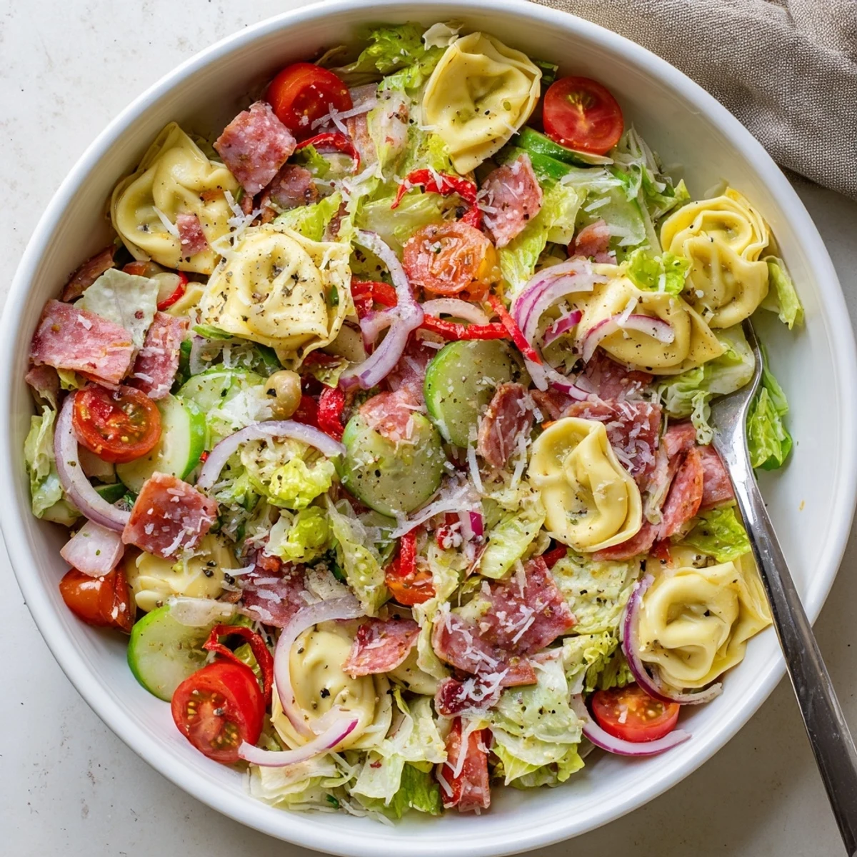 Colorful bowl of fresh grinder tortellini salad recipe with cheese tortellini, crisp vegetables, and zesty Italian dressing garnished with grated Parmesan