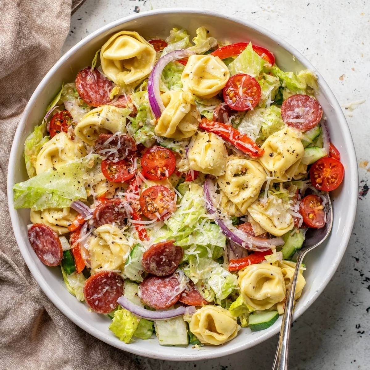 Vibrant Italian-American grinder tortellini salad recipe with crisp lettuce, sliced red onion, cucumber, and optional salami tossed in herb vinaigrette