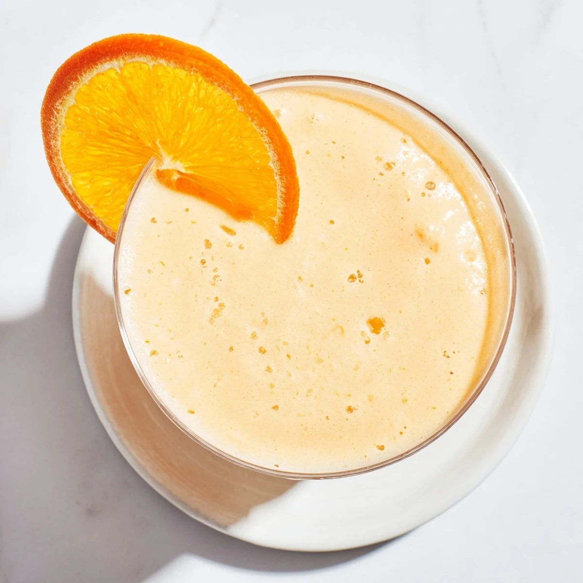 Sun Kissed Frozen Orange Cream Slush in a tall glass with fresh orange slice garnish