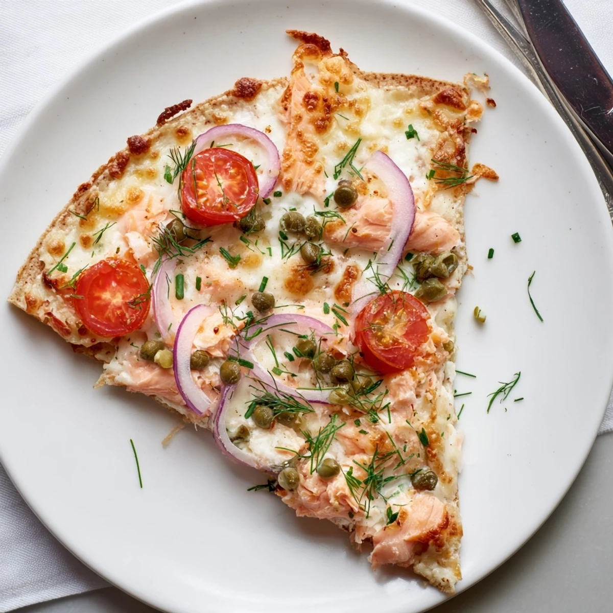 Golden, crispy leftover salmon tortilla pizza topped with melted mozzarella, fresh tomatoes, and red onion slices.