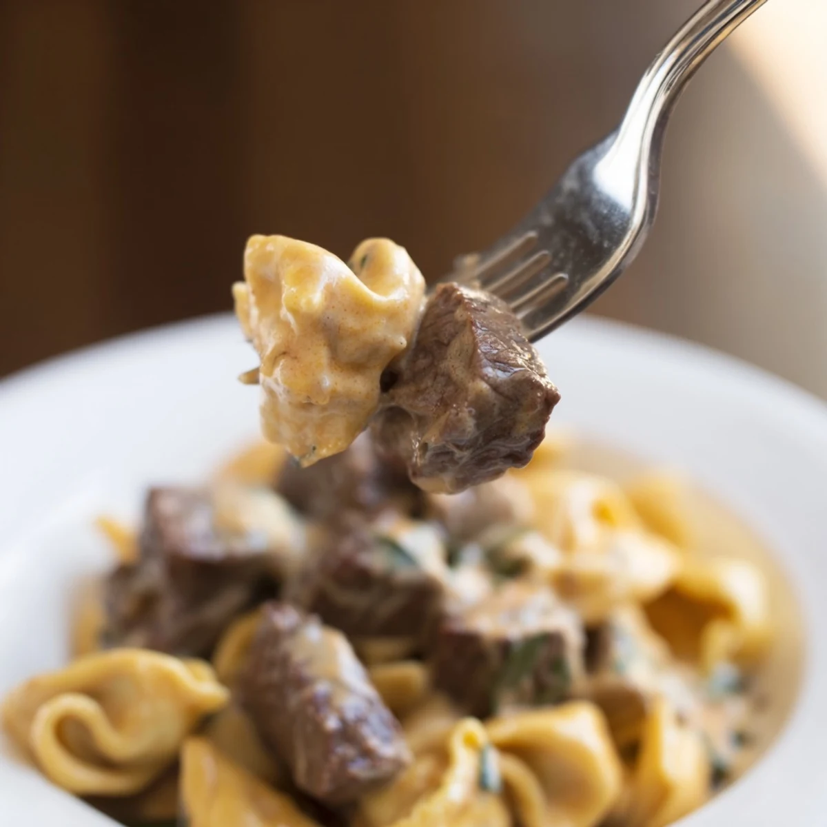 Close-up of tender beef tortellini coated in a thick white garlic parmesan glaze
