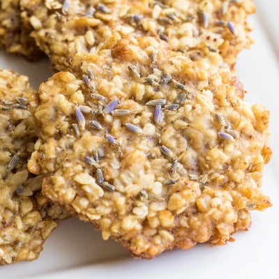 Crisp lavender honey crunch cookies drizzled with white chocolate beside a steaming teacup