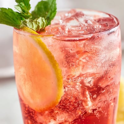 Sparkling Honey Lemon Pink Soda poured over ice with lemon slices